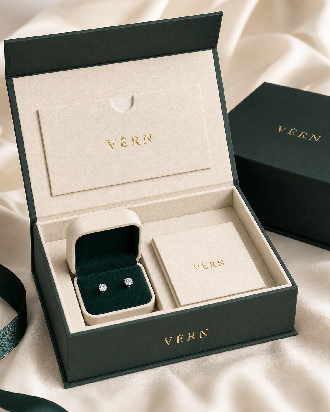 딥그린과 크림 색상의 실제 VÈRN 프레젠테이션 케이스 안에 라운드 스터드 이어링이 놓인 모습